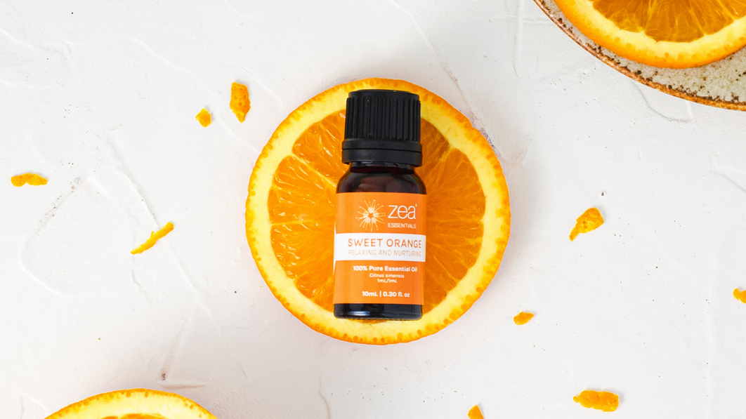 Bottle of Zea Sweet Orange essential oil styled with fresh orange slices
